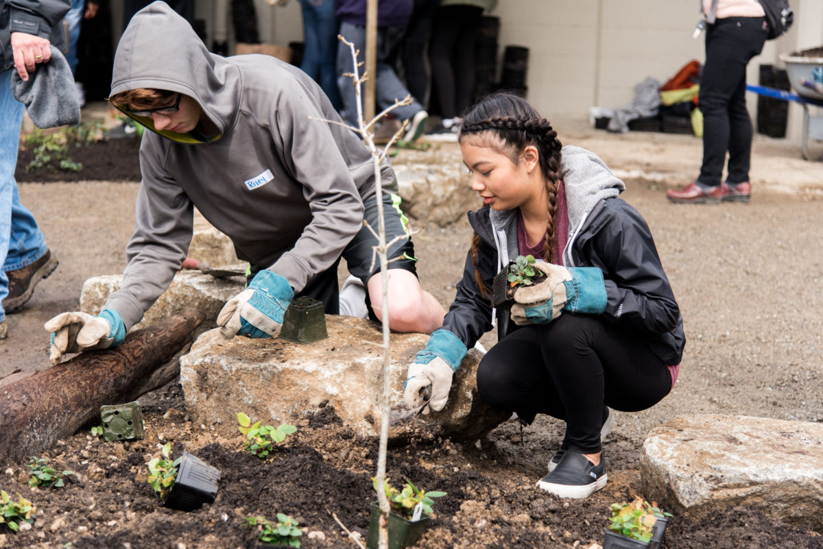 2 students wearing gloves planting in Sylvester Middle School's new rain garden