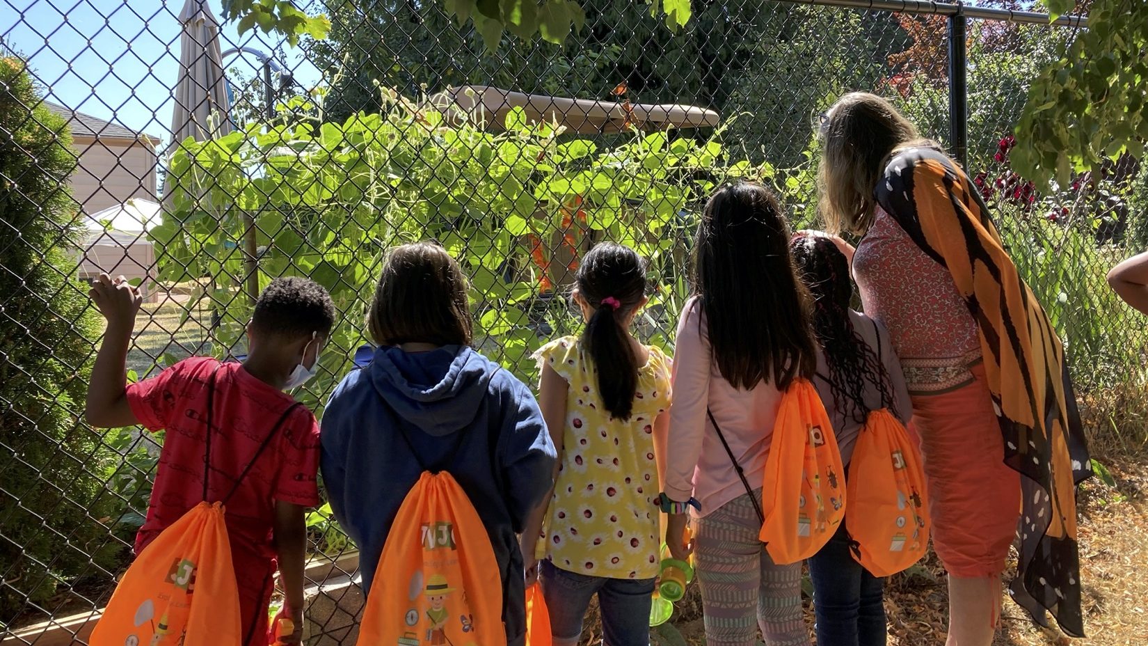 A large group of Tukwila School District students examine plants on a garden tour. 