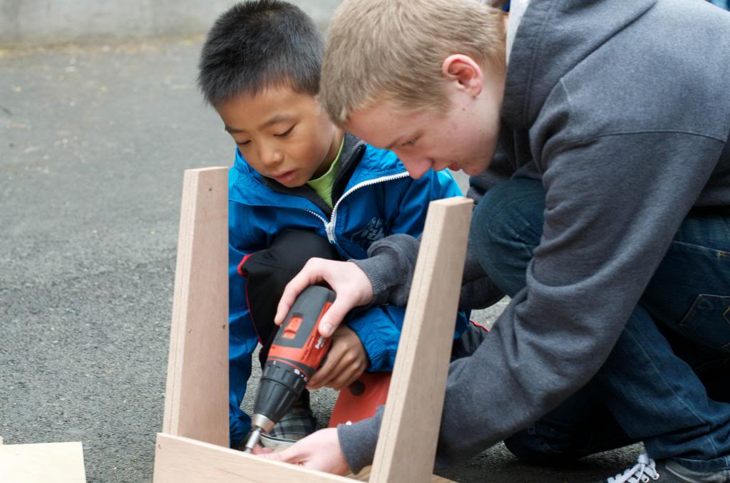 A student and volunteer drill together a piece of the bench at a Day of Service in 2013