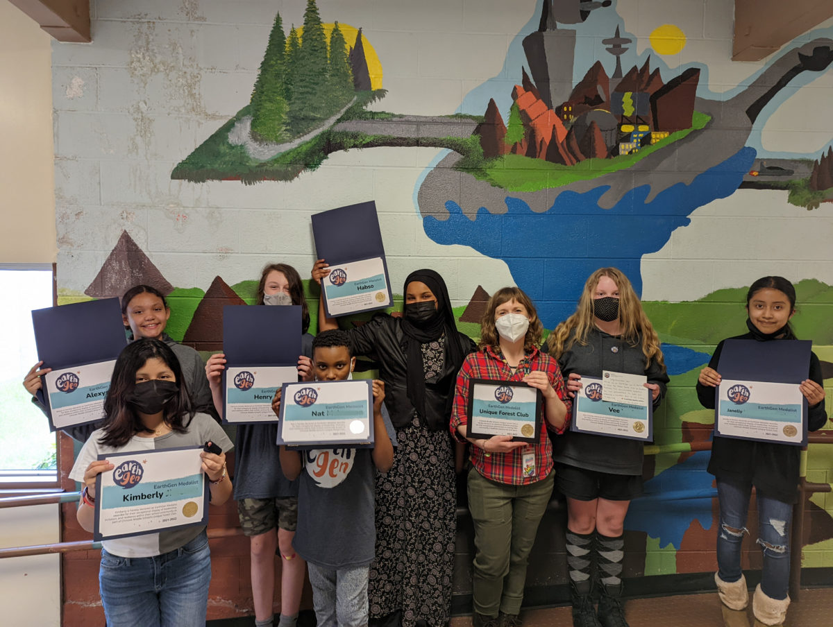 A group of students from Chinook Middle School's Unique Forest Club hold up their certificates after being honored as EarthGen Medalists.
