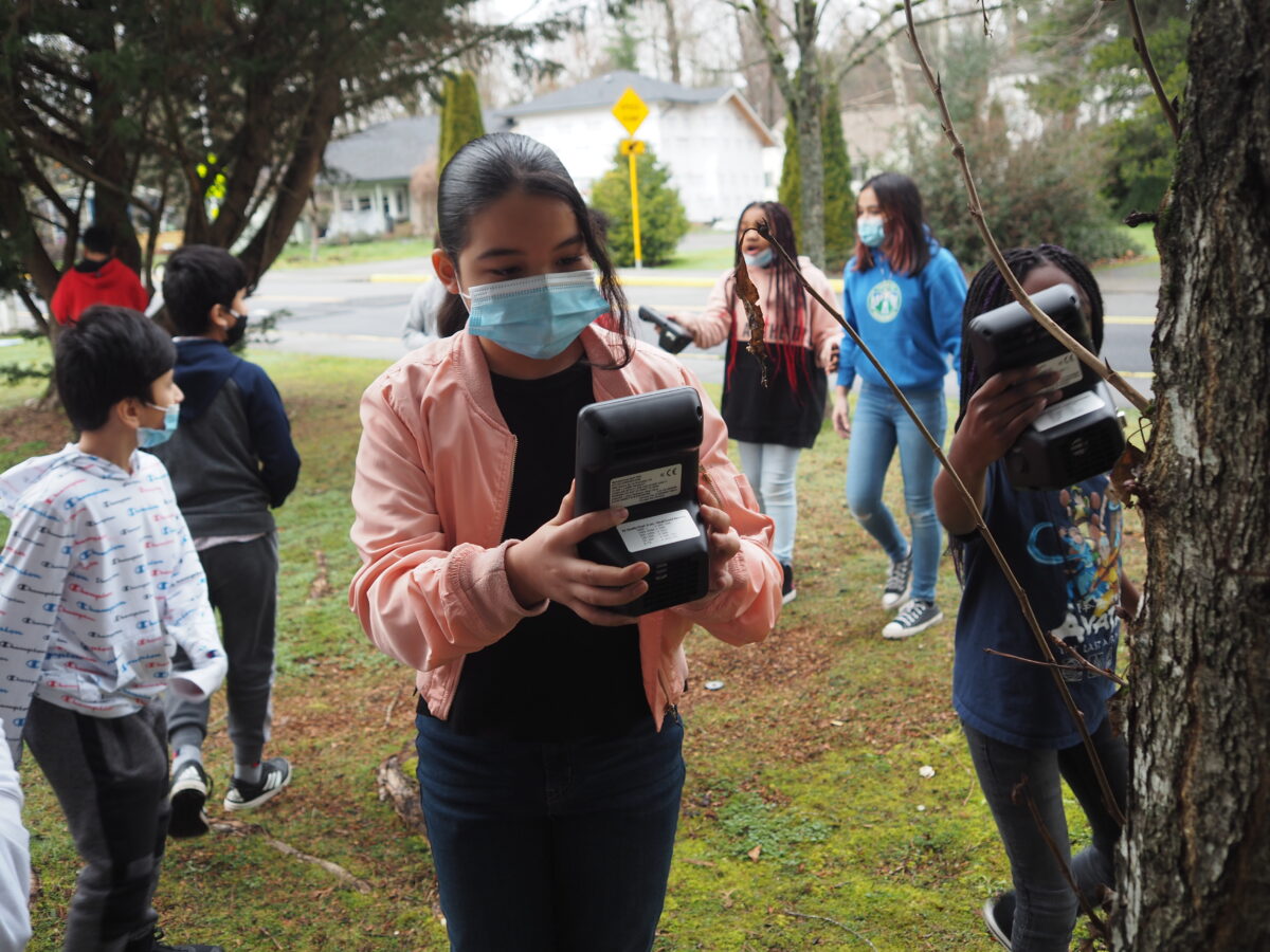 A student holds an air quality meter and examines the numbers.