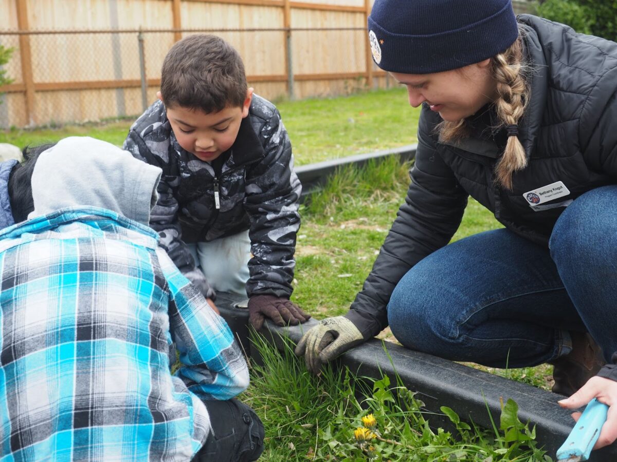 Bethany Kogut helps a group of students identify weeds in the garden.