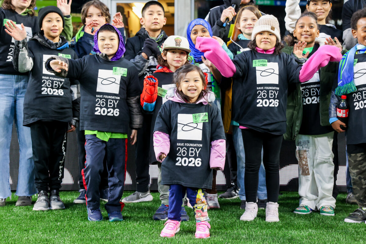 A close up of Rising Star Elementary students waving at the camera while being recongnized as RAVE Community Kids of the Match at the Seattle Sounders FC game.