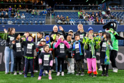 Rising Star Elementary students smile and wave at the camera while being recongnized as RAVE Community Kids of the Match at the Seattle Sounders FC game.