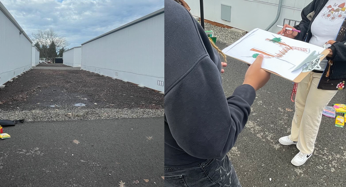 A barren brown patch of dirt and asphalt is visible between 2 portable buildings at Tyee's interim campus. Students hold a clipboard that shows their ideas to improve their campus. 
