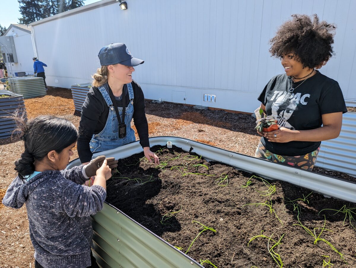 Students plant plants in a new raised bed alongside an EarhGen staff person
