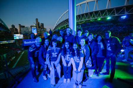 A group of EarthGen board members, staff, and partners stand on the Flag Deck at the Seattle Seahawks game