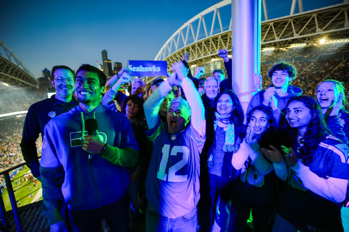 A group of EarthGen board members, staff, and partners stand on the Flag Deck leading the SEA - HAWKS chant at the Seattle Seahawks game