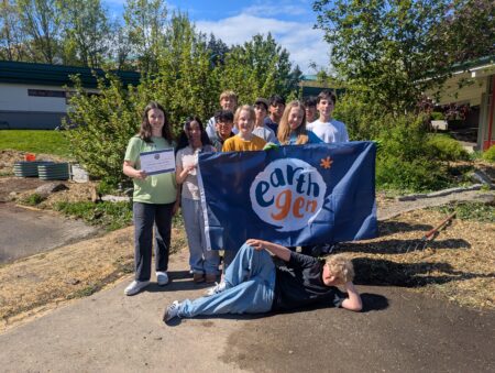 A group of students pose with the EarthGen flag