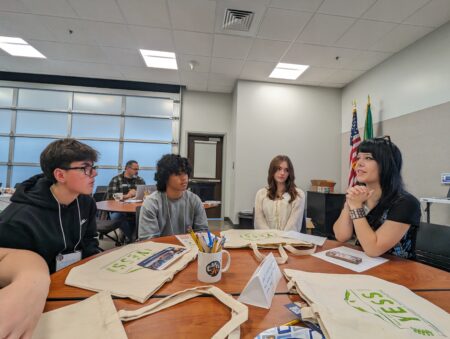 4 students sit at a table engaged in a dialogue
