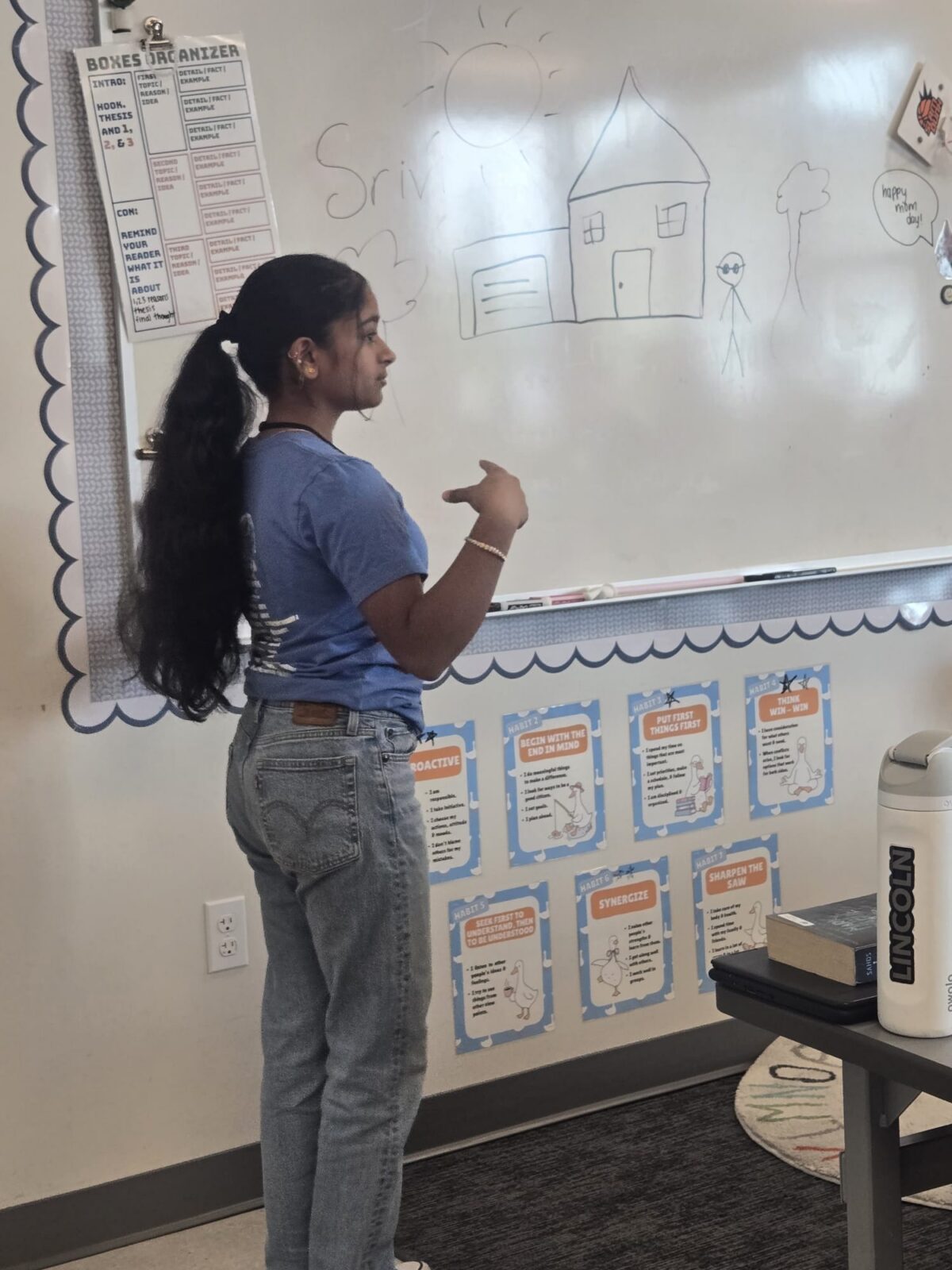 Srivi stands at a white board while teaching an elementary school class
